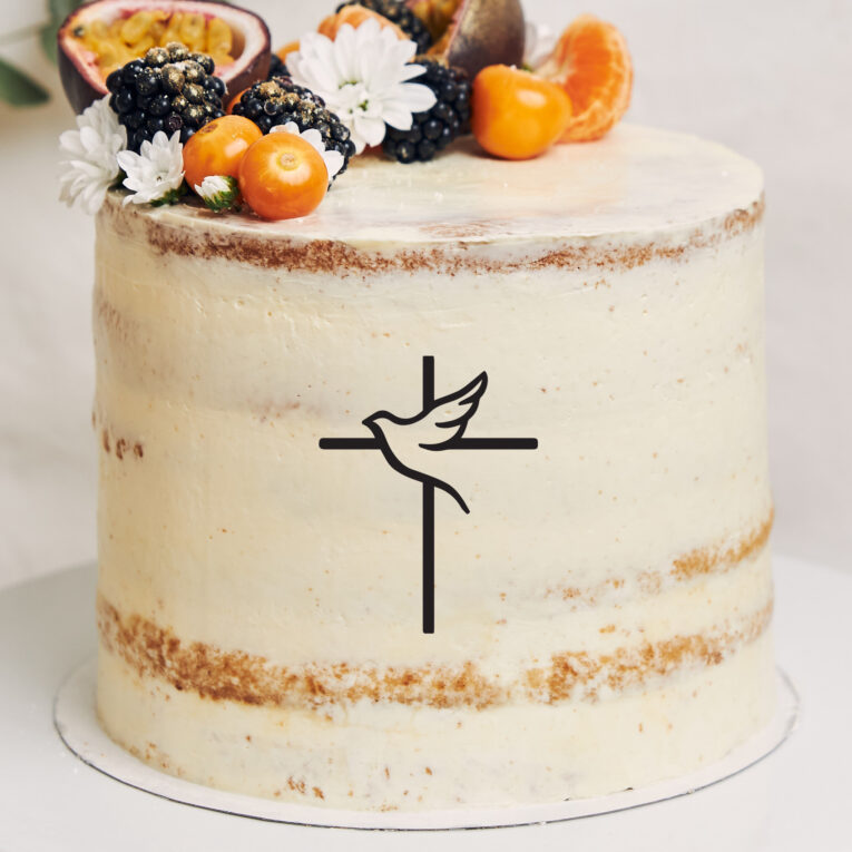 White cake with berries and passionfruits next to a plant behind a white background